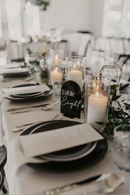 close up of the table set up, black charger and grey plate, white menu card and white napkin, candles lined down the table, Orlando, FL