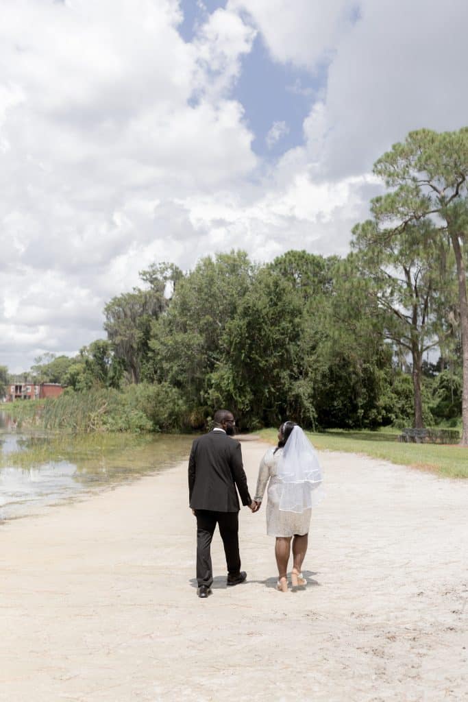 bride and groom walking hand in hand on the sand, near the water, Orlando, FL