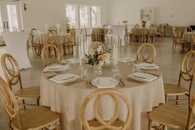 round tables, wooden chairs, tan tablecloths, white plates, small floral centerpiece, Orlando, FL
