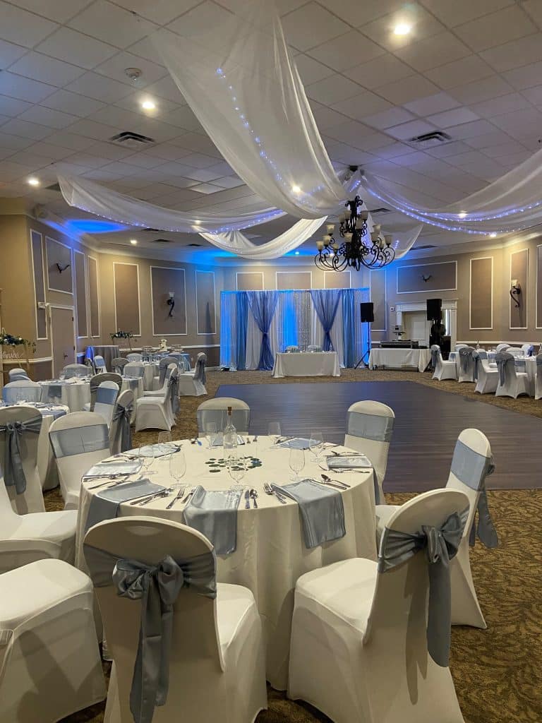 ballroom at Ventura Country Club, blue uplighting, dance floor, round tables with chair covers, light blue bows, Orlando, FL