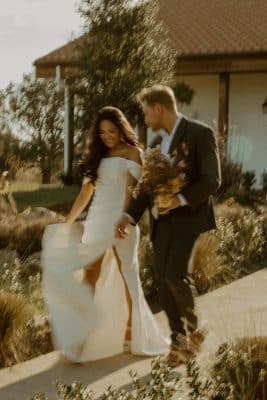 bride and groom walking together hand in hand, groom carrying her bouquet, Sterling Event Venue, Orlando, FL