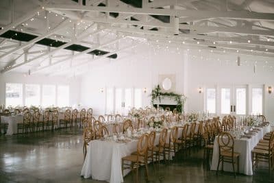 indoor reception set up, long tables, dance floor in the center of the room, white walls, white rafters, wooden chairs, Orlando, FL