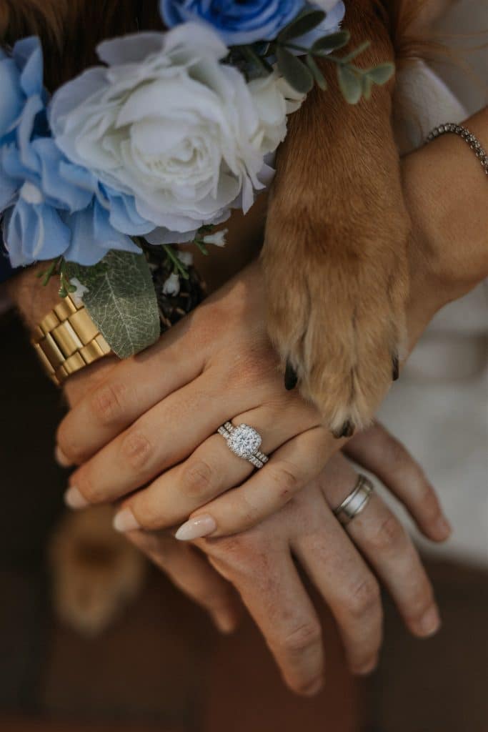 bride and groom crossing their hands, with their rings, dog paws also included, blue and white flowers, Nexum Photography, Orlando, FL