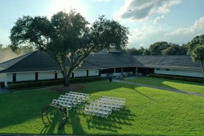 aerial view of the outdoor wedding ceremony set up, white chairs in rows, landscaped lawn, large tree, Orlando, FL