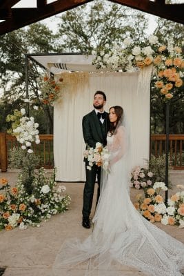 bride and groom posing for the camera, at the altar surrounded by flowers, outside, Orlando, FL