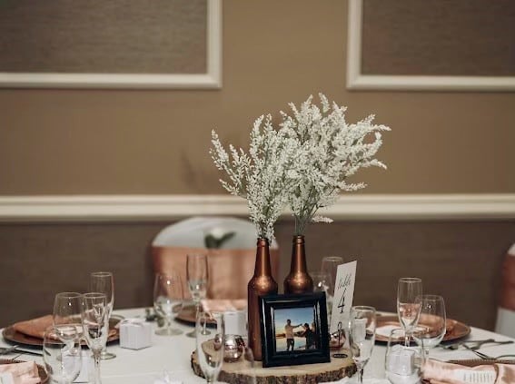 table set up, two gold bottles and a photo frame on a wood disc as a centerpiece, Ventura Country Club, Orlando, FL