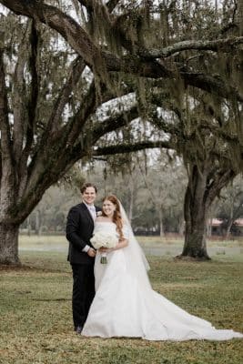 bride and groom in their wedding attire, standing in front of a couple of trees, outdoors, Orlando, FL