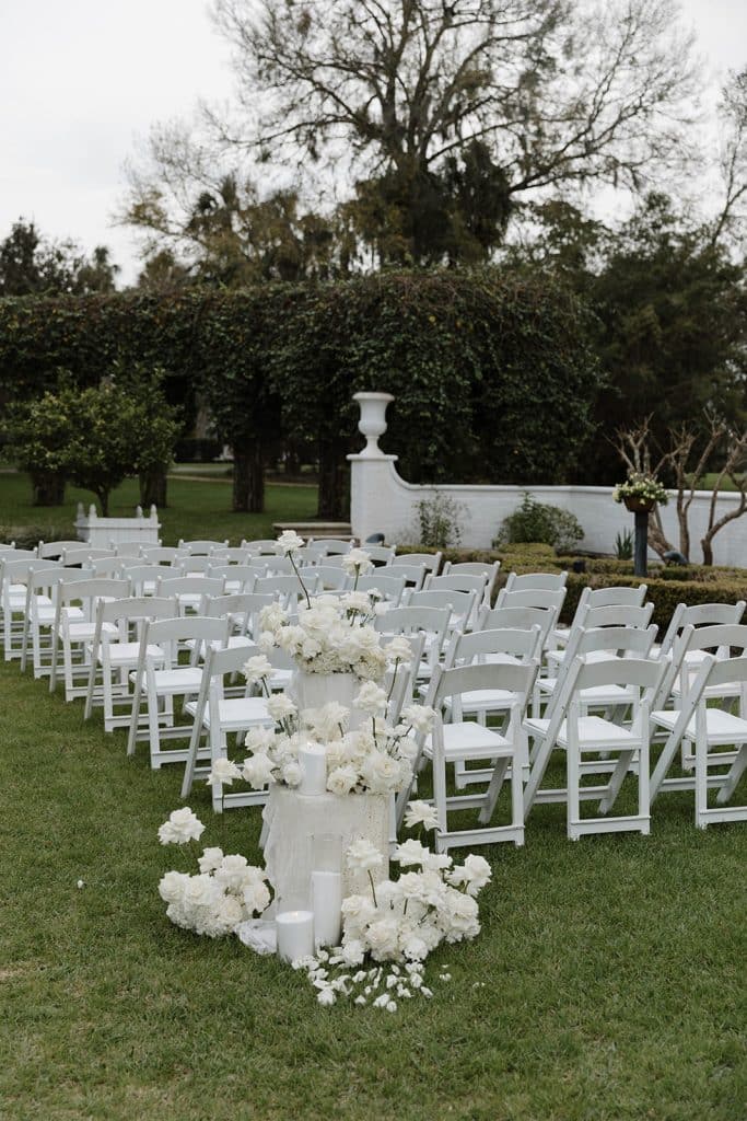 ceremony set up, rows of white chairs, white podium columns with white flowers atop, outdoors, Orlando, FL