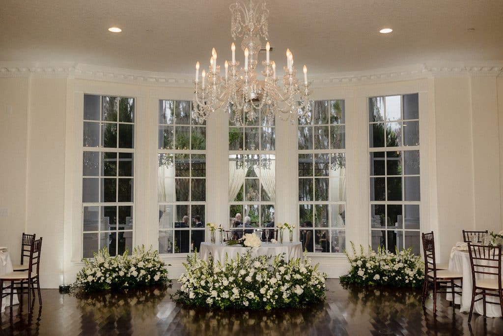 ballroom, large doors with windows, large chandelier, white floral bunches along the floor, Melanie Paige Events + Design, Orlando, FL