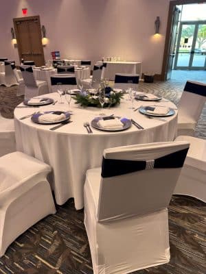 reception table, white chairs with white chair covers, silver and blue bows, silver chargers, white napkins, Orlando, FL