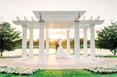 white pergola, outside, near water, trees on each side, bride and groom under the pergola, Orlando, FL