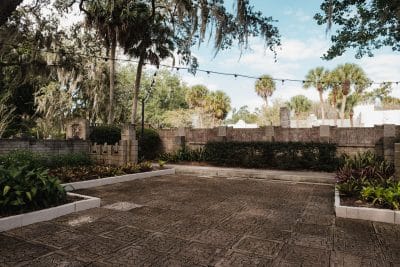 large patio area, palm trees in the distance, plants and walls surrounding the stone patio, Art & History Museum, Orlando, FL