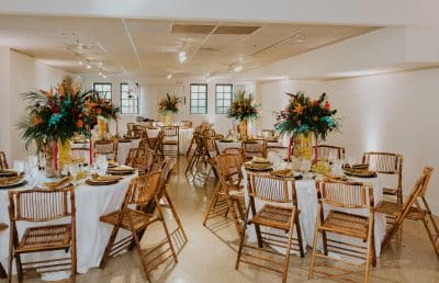 indoor set up for a reception, large tall, floral arrangements on the center of the tables, wooden chairs, white tablecloths, Orlando, FL