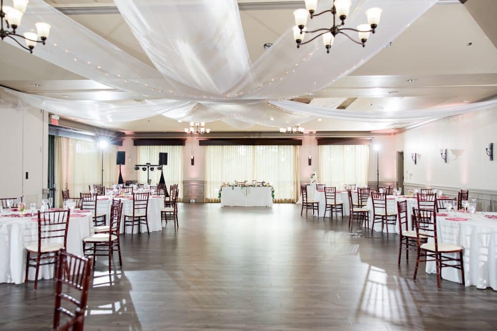 large reception hall, wood floors, white curtains, white lighting, white tablecloths with brown chairs, head table, Falcon's Fire Golf Club, Orlando, FL