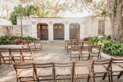 outdoor ceremony set up, concrete and stone walls with three entrances, wooden chairs, patio area, Orlando, FL