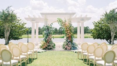 wedding ceremony set up, outside, metal arch with flowers adorned, near water, Orlando, FL