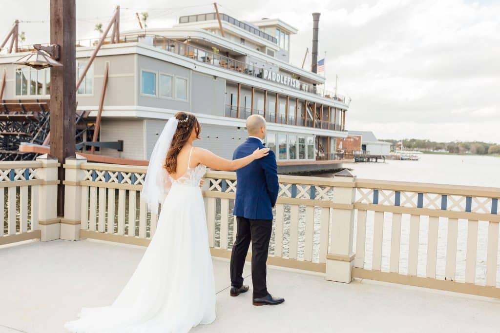 bride standing behind her groom, looking into the distance, Paddlefish off to the left in the water, Orlando, FL