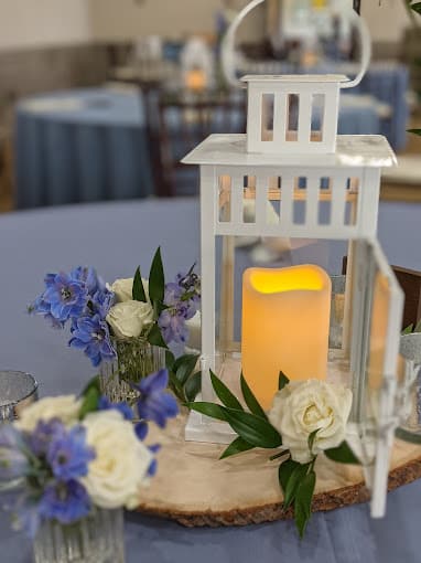 centerpiece, battery operated candle inside a white metal lantern, purple and white flower display on top of a wooden circle, Orlando, FL