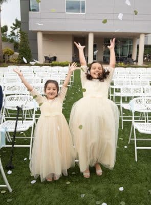 two flower girls in their off white dresses raising their hands in excitement after the ceremony, The Celeste Hotel, Orlando, FL