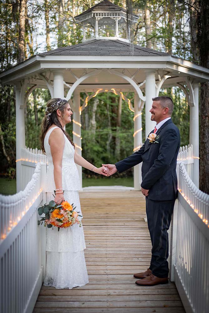 bride and groom holding hands on a bridge, gazebo in the background, Orlando, FL