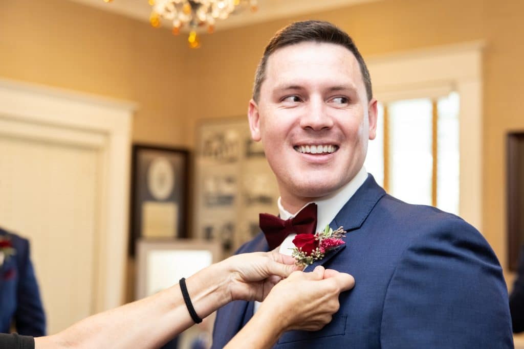 groom image getting pinned for boutonnière, 