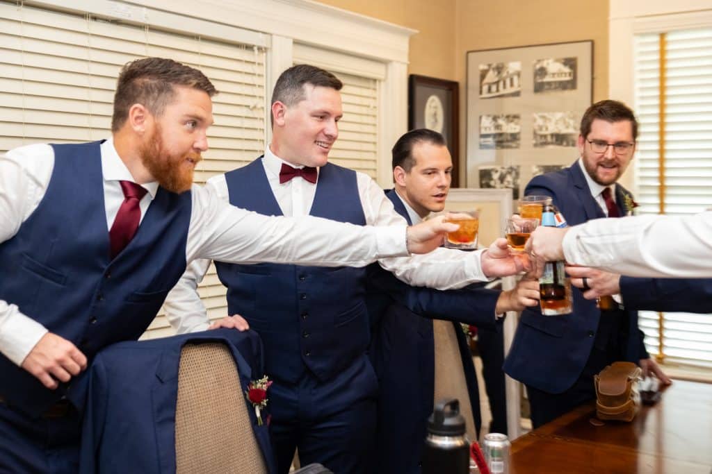 groom cheering with groomsman for his burgundy and navy wedding