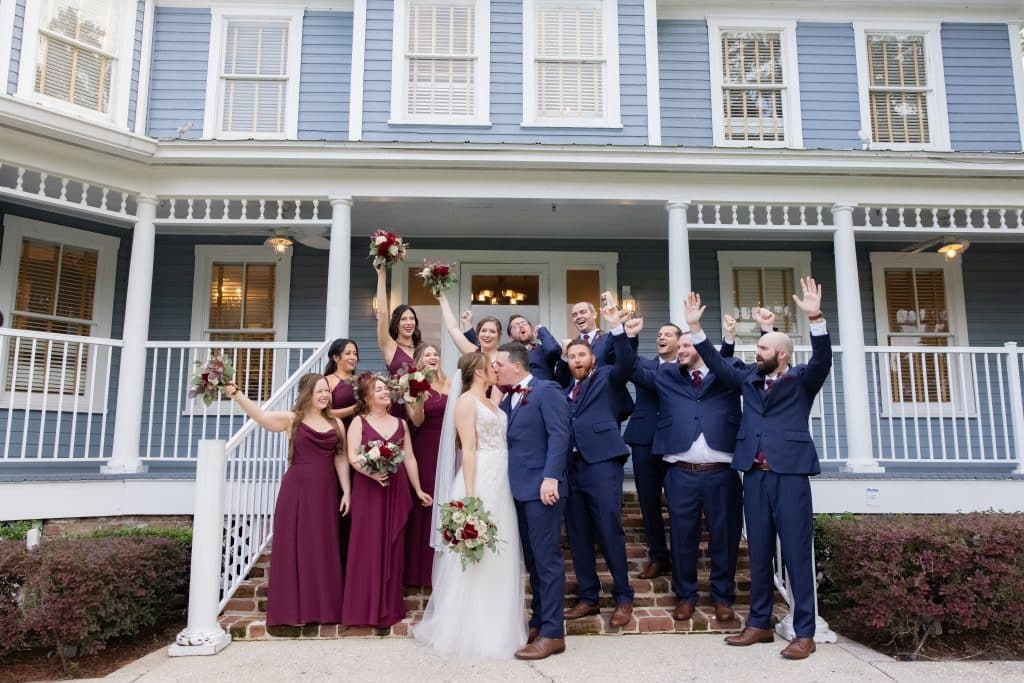 bridal party in burgundy and navy colors for wedding cheering on the couple