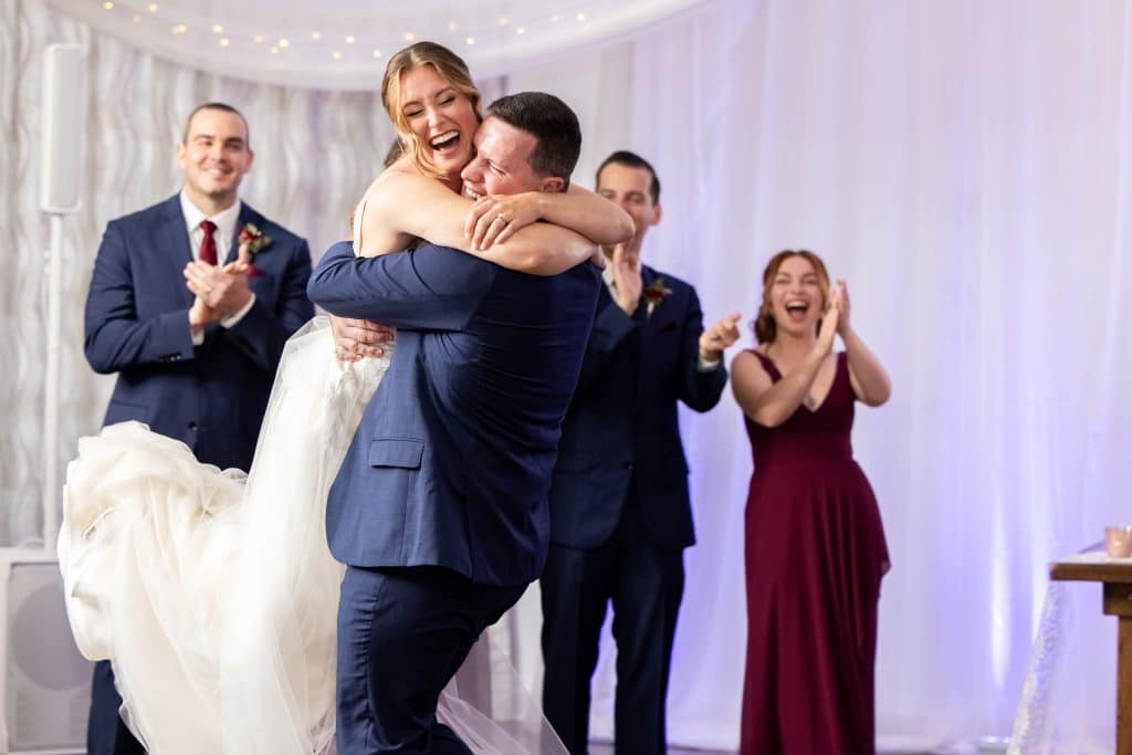 groom carrying bride on their first dance for their burgundy and navy wedding
