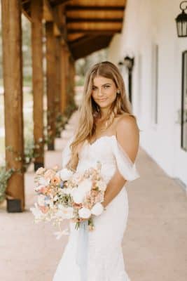 bride in her strapless gown, holding her beautiful bouquet, standing on the front porch area of the Sterling Event Venue, Orlando, FL