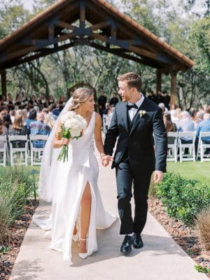 bride and groom smiling at each other, hand in hand, walking away from their ceremony area, Orlando, FL