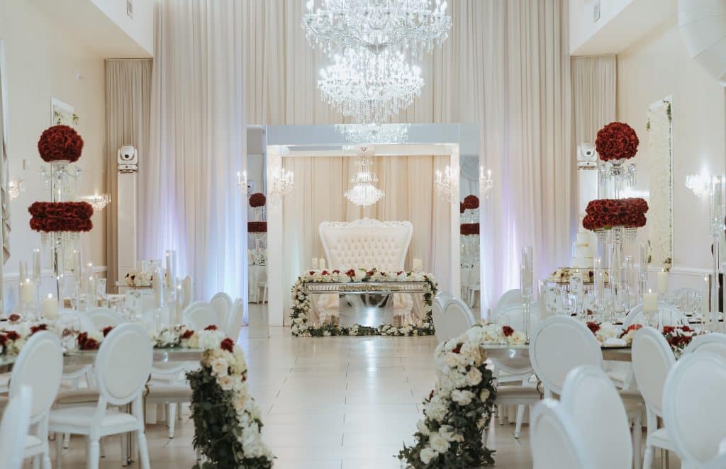 wedding reception set up, head table at the front, surrounded by round tables, large floral arrangements of red roses, table runners with flowers across them, Veranda Elegant Events, Orlando, FL