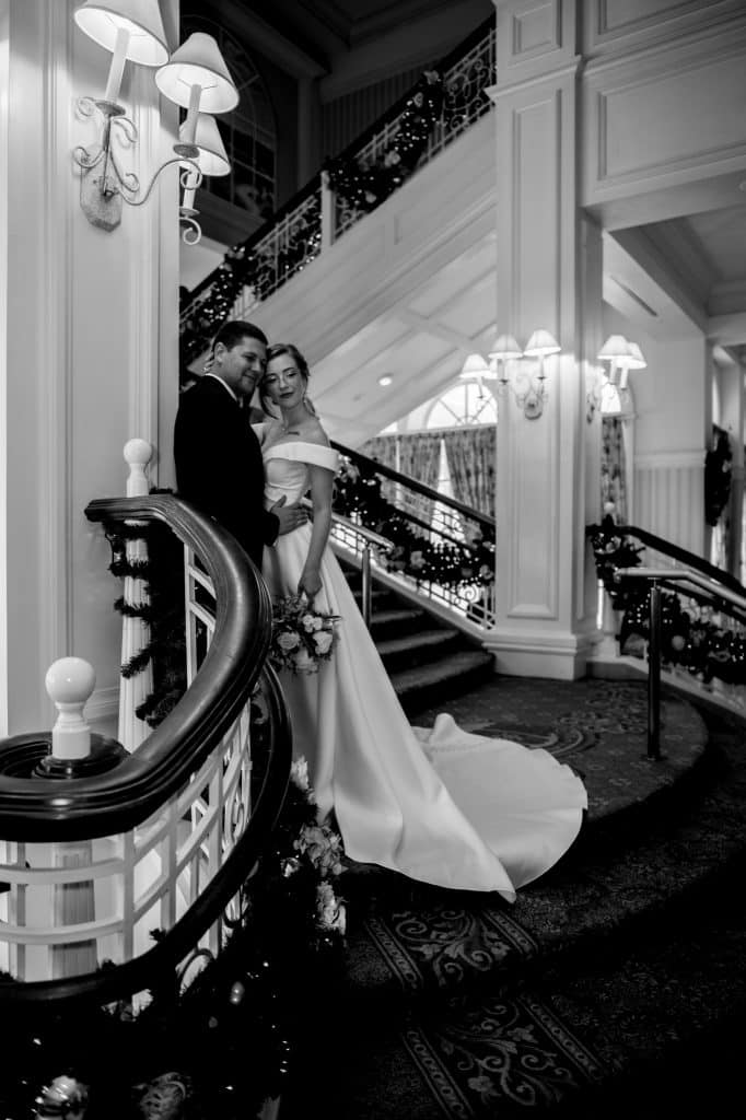 black and white image of bride and groom down the stairs at Disney's Grand Floridian Resort celebrating Festive Christmas Disney Wedding