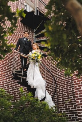 bride and groom on their wedding day posing on a spiral metal staircase, brick wall, Northwest Square Events, Orlando, FL