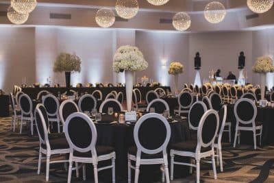 ballroom set for a dinner reception, large white floral centerpieces, white globe lights, black and silver chairs, black tablecloths, Renaissance Orlando Resort and Spa, Orlando, FL