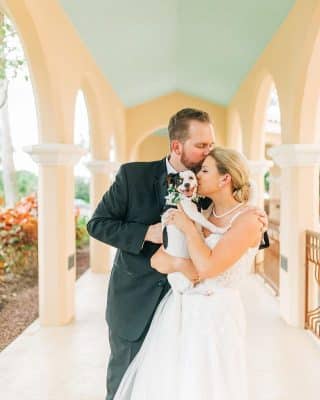 bride and groom embracing with their dog in the bride's arms, in the outdoor hallway of the venue, Rosen Shingle Creek, Orlando, FL