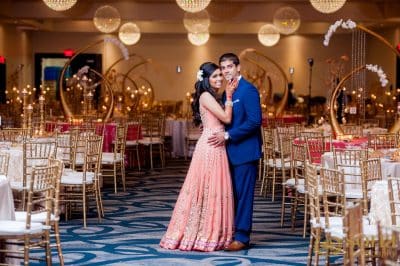 mand and woman in the ballroom, woman in a pink dress, man in a blue suit, globe lights, gold uplighting, gold chairs with white cushions, Renaissance Orlando Resort and Spa, Orlando, FL