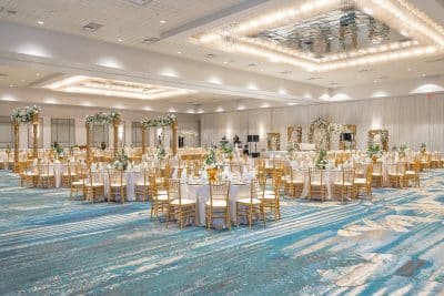 ballroom set for a wedding reception, gold chairs with white seats, green and white floral garlands throughout the room, Rosen Centre, Orlando, FL