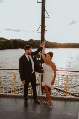 bride and groom raising their hands, held together at the bow of the ship, Orlando, FL