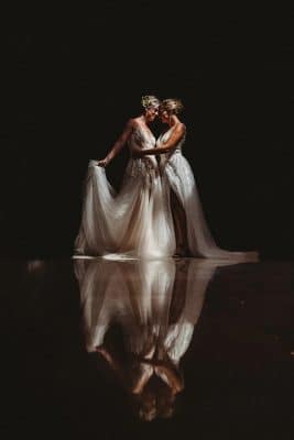two brides in their wedding gowns, embracing each other, black background, mirror image on the floor, Renaissance Orlando Resort and Spa, Orlando, FL