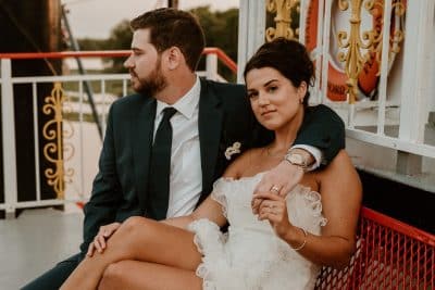 close up of the wedding couple, sitting on a bench, groom's arm around his bride, on board the riverboat, Orlando, FL