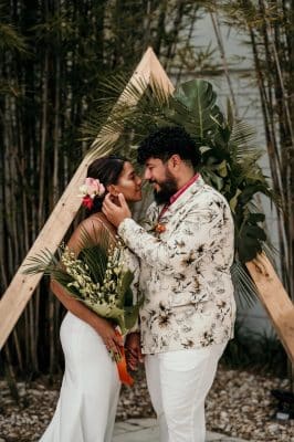 bride and groom standing in front of a triangle altar, green floral leaves, couple embracing, Orlando, FL