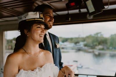 bride and groom on the boat, bride wearing the captain's hat, wedding day, Orlando, FL