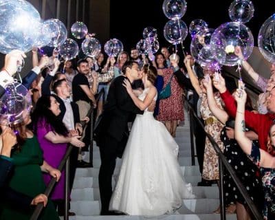 bride and groom kissing with their guests surrounding them on stairs, bubbles, Orlando, FL