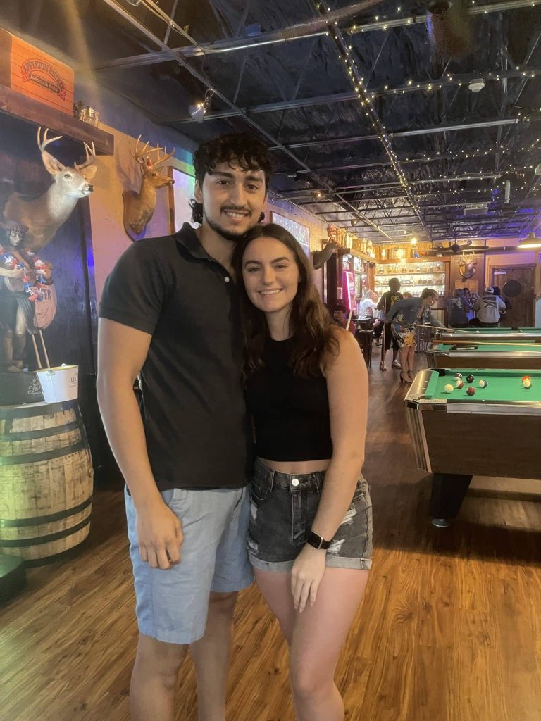 couple smiling at a restaurant with pool table in the back