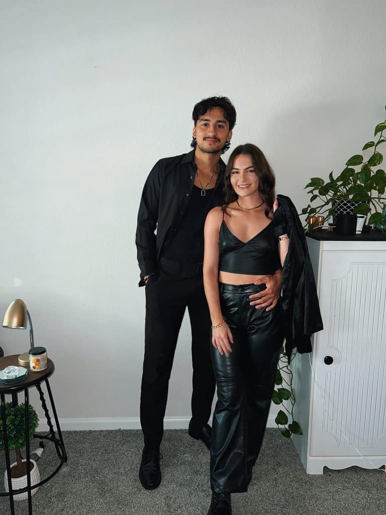 couple posing with black outfits with a white background