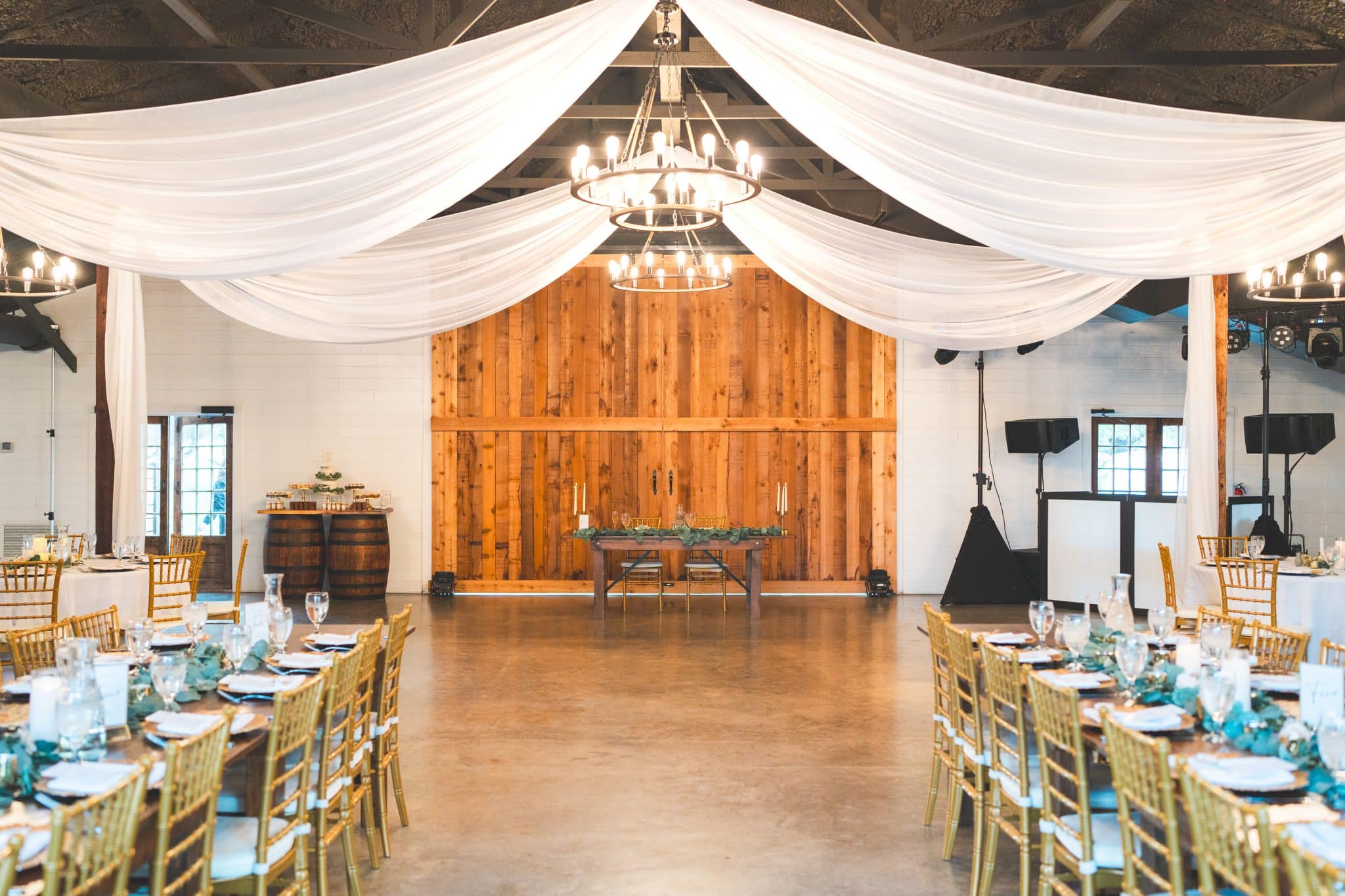 Indoor reception space for Moss Estates with gold chivalry chairs and chandelier in front of two large wooded doors with draping 