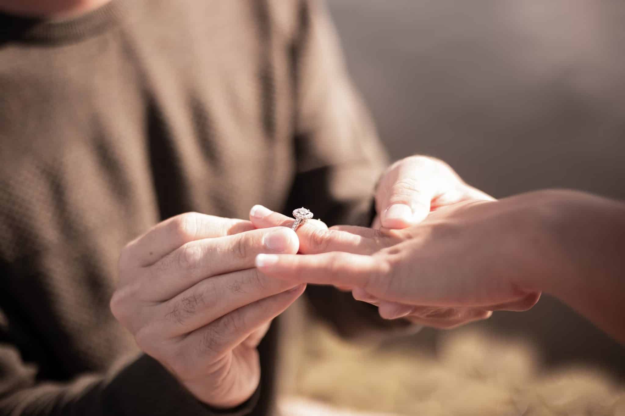 groom adding engagement ring to their fiance