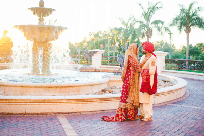 man and woman in traditional Indian wedding attire, standing in front of the fountain, Orlando, FL