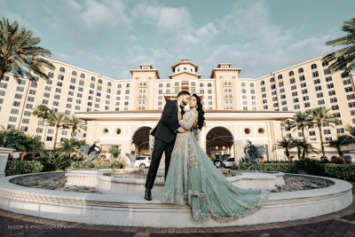 bride and groom standing on the edge of the fountain, hotel in the background, Rosen Shingle Creek, Orlando, FL