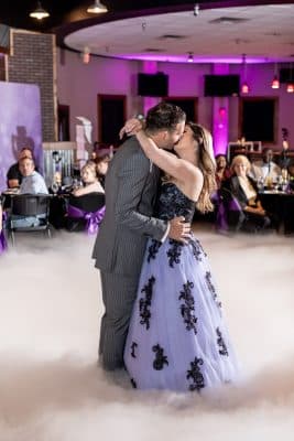 wedding couple dancing on the dance floor, kissing, bride in purple and black dress, purple uplighting, Orlando, FL